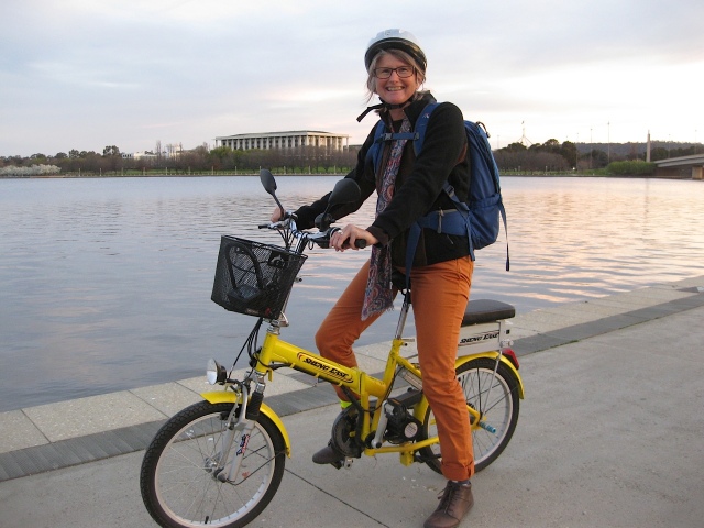 The cute little yellow electric bike by Lake Burley Griffin with The National Library in the background.